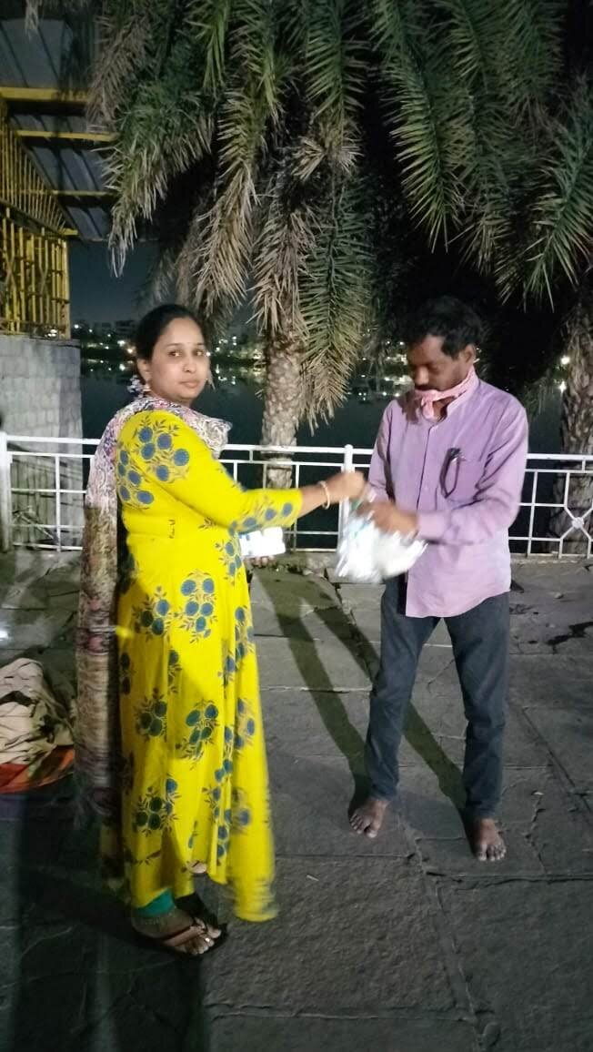 Volunteer handing a food packet to a man at night